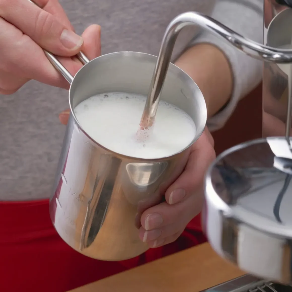 barista pouring milk into a metal cup