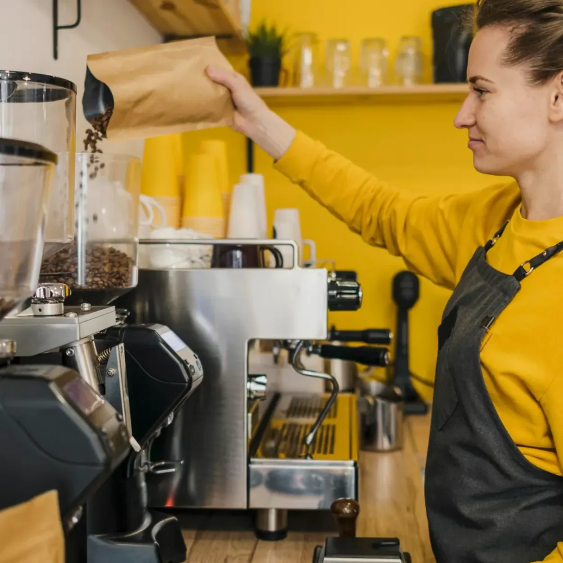 barista pouring coffee beans in an espresso machine
