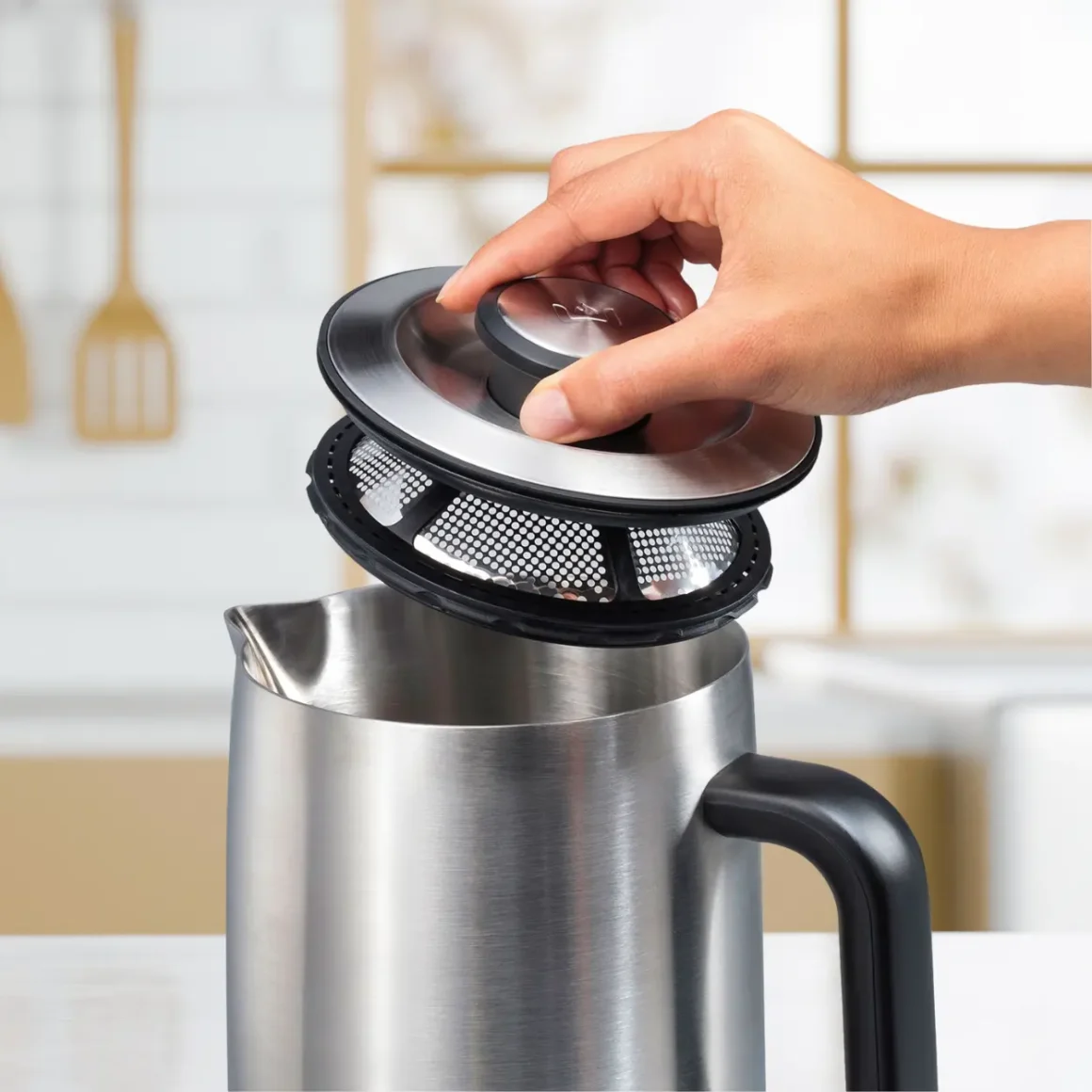 a hand holding a lid over a wolf gourmet true temperature electric kettle