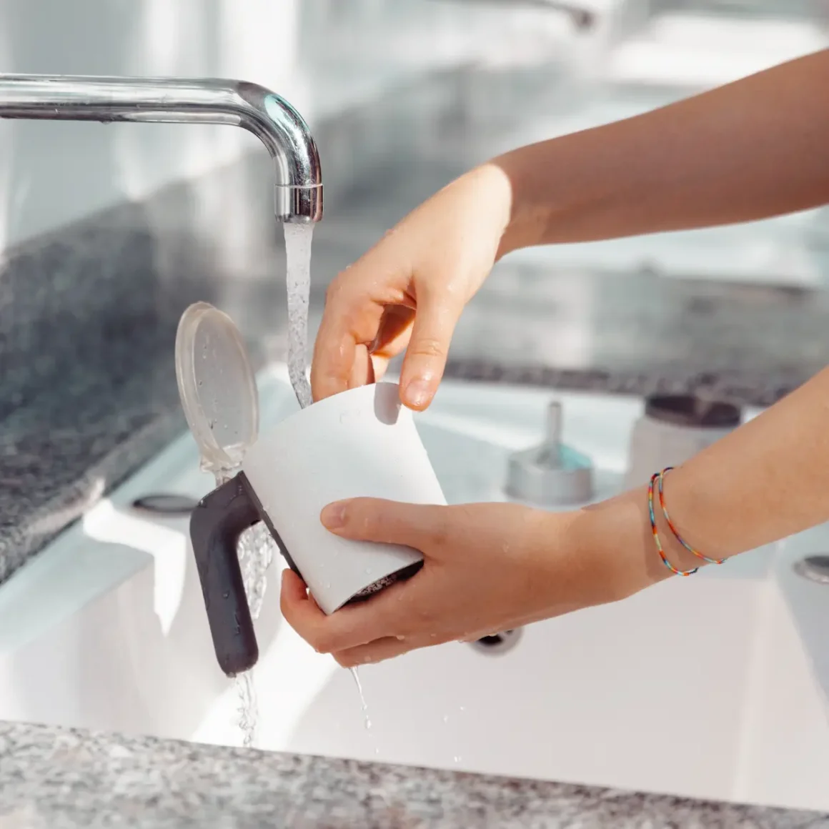 a person washing a moka pot in a sink