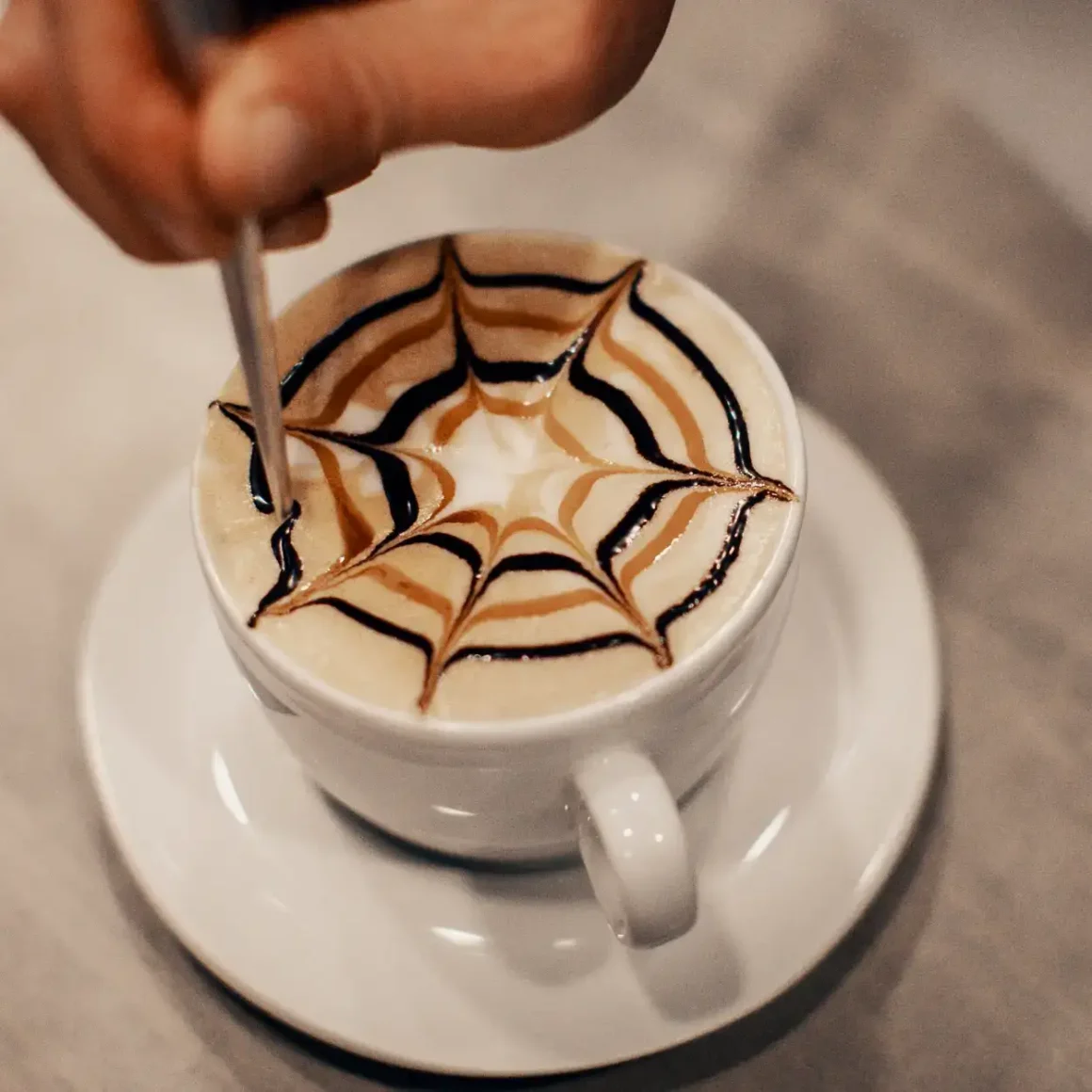barista making design on the top of a cup of mocha