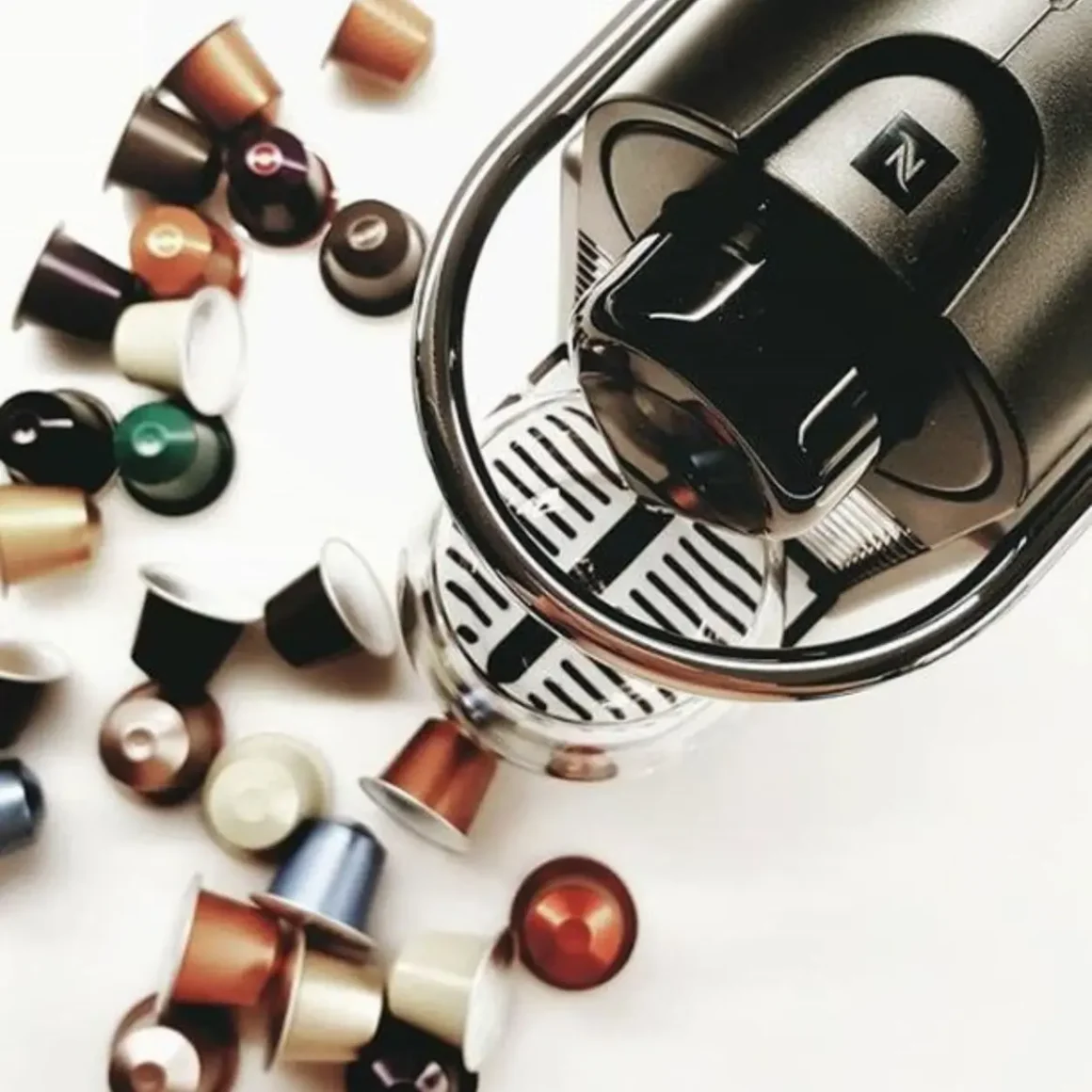 a nespresso pixie espresso machine with a group of coffee capsules