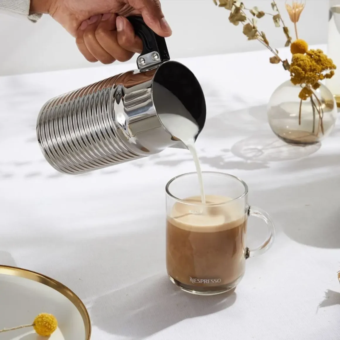 a person pouring milk into a cup of coffee
