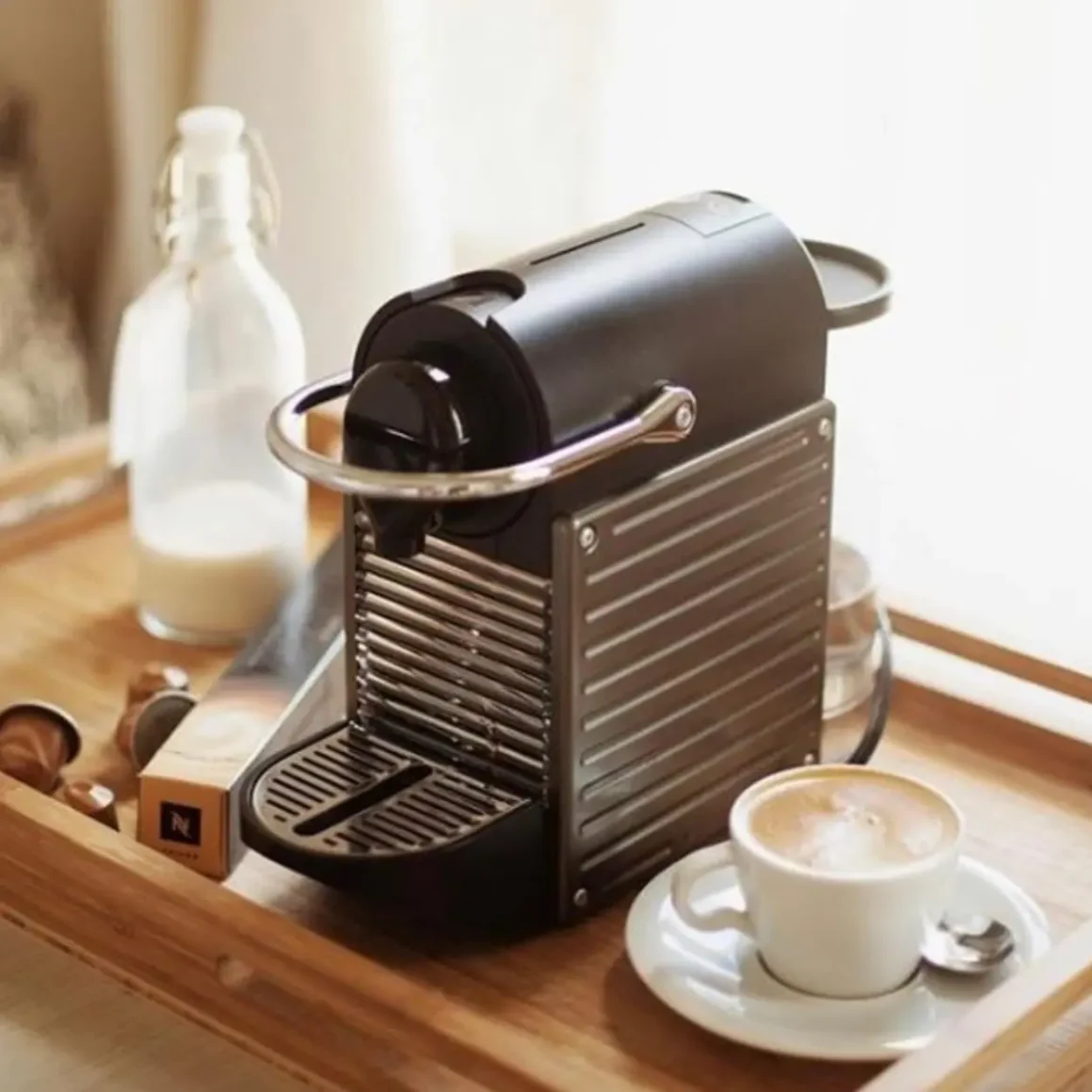 a nespresso pixie espresso machine and a cup of coffee on a tray