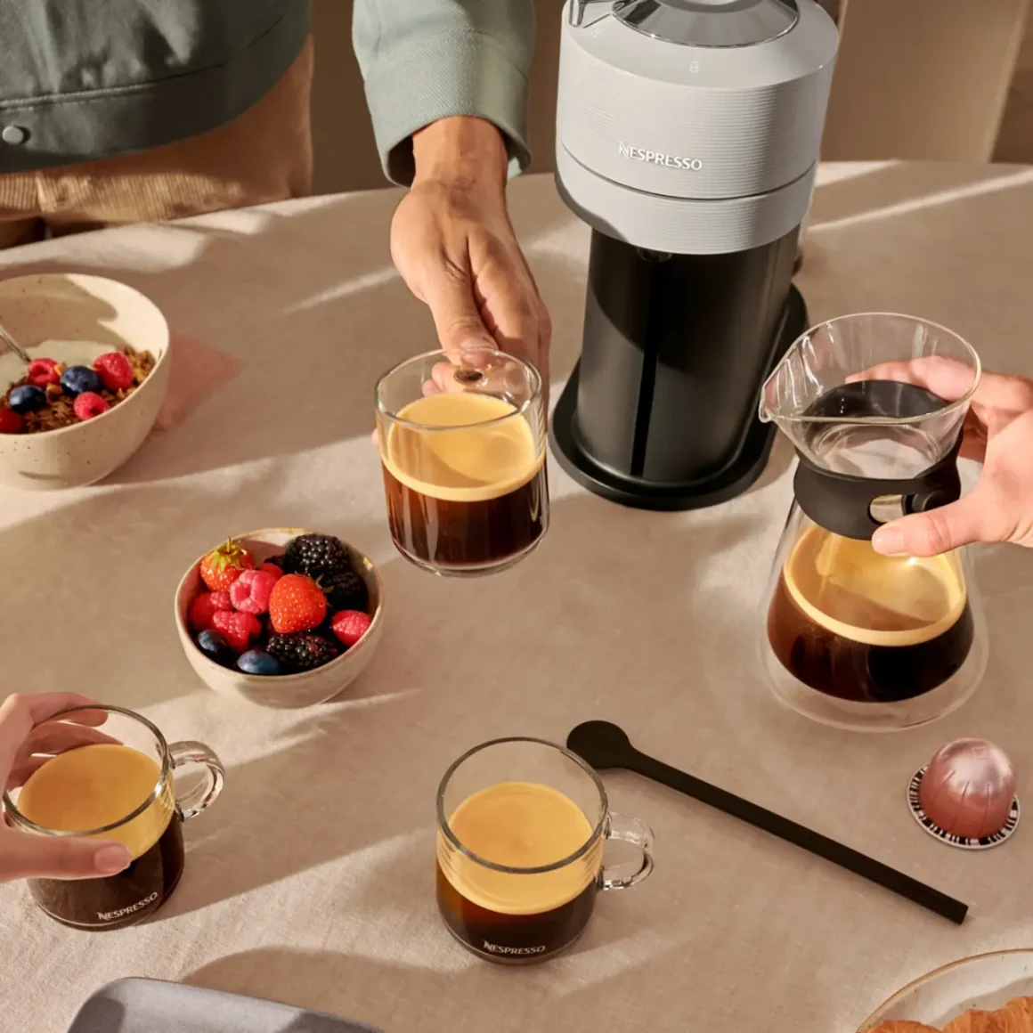 a nespresso machine and a group of people holding cups of coffee