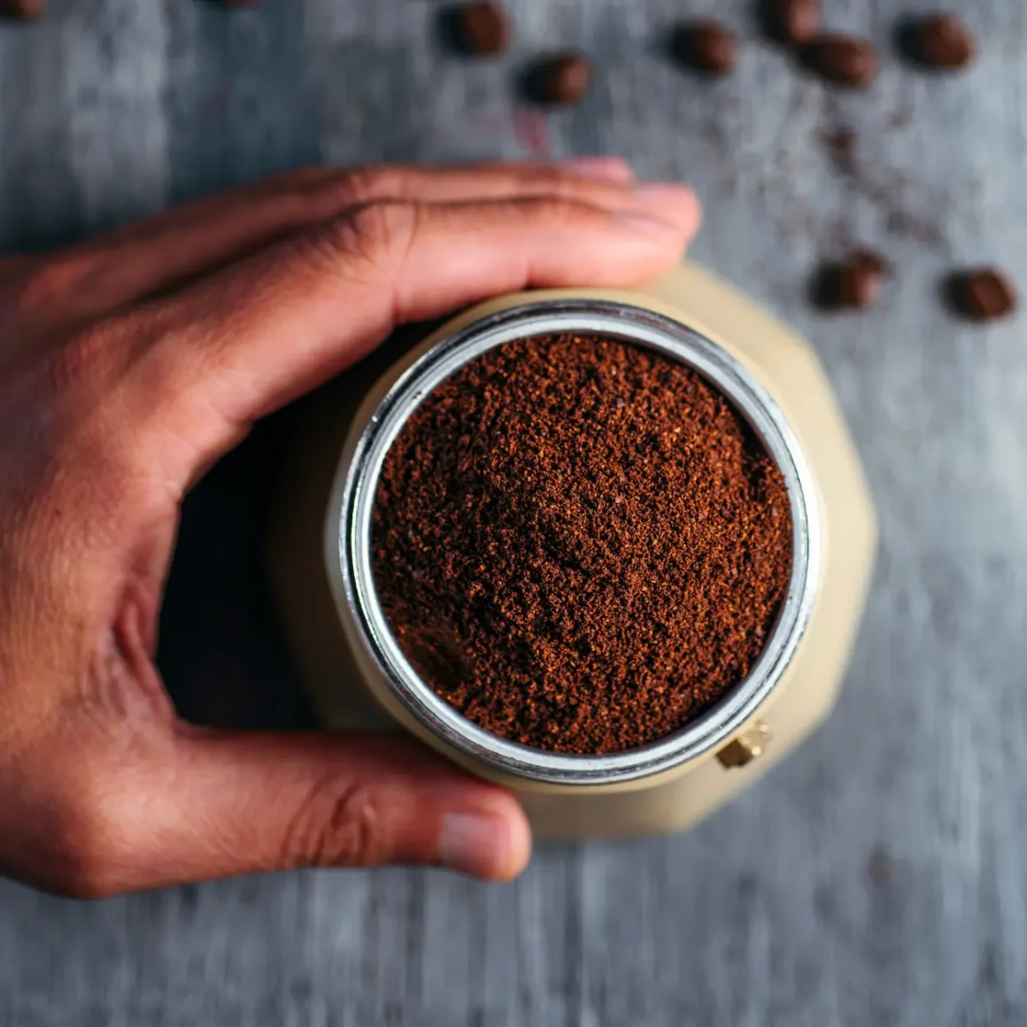 a hand holding a jar of ground coffee