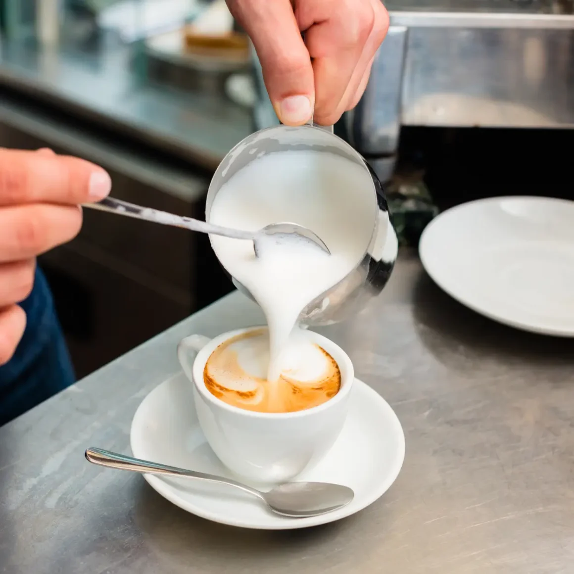 barista preparing cafe con leche by pouring milk in a cup