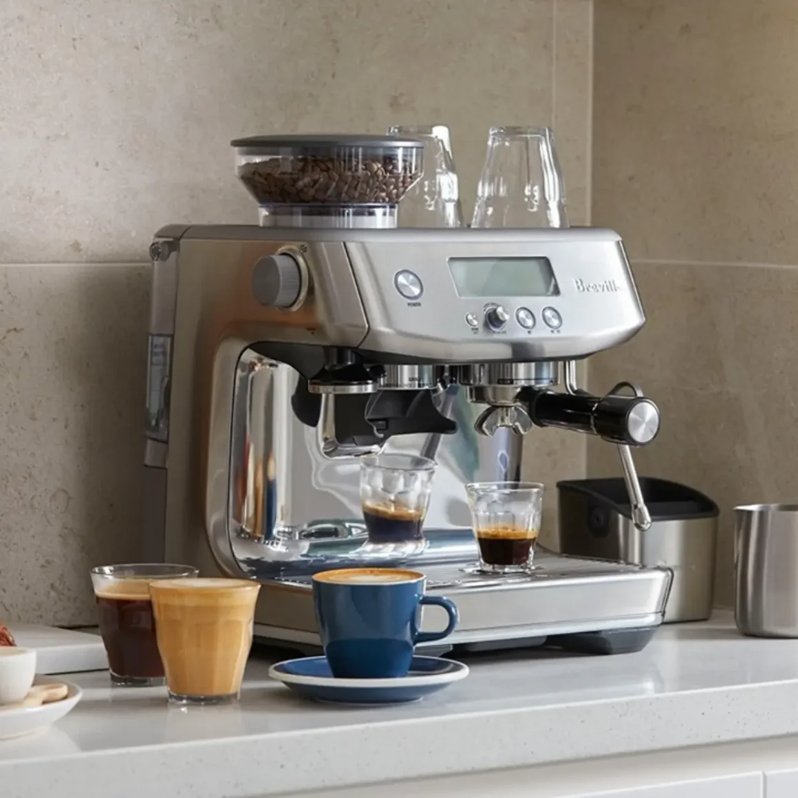 a breville barista pro espresso machine with cups and glasses on a counter