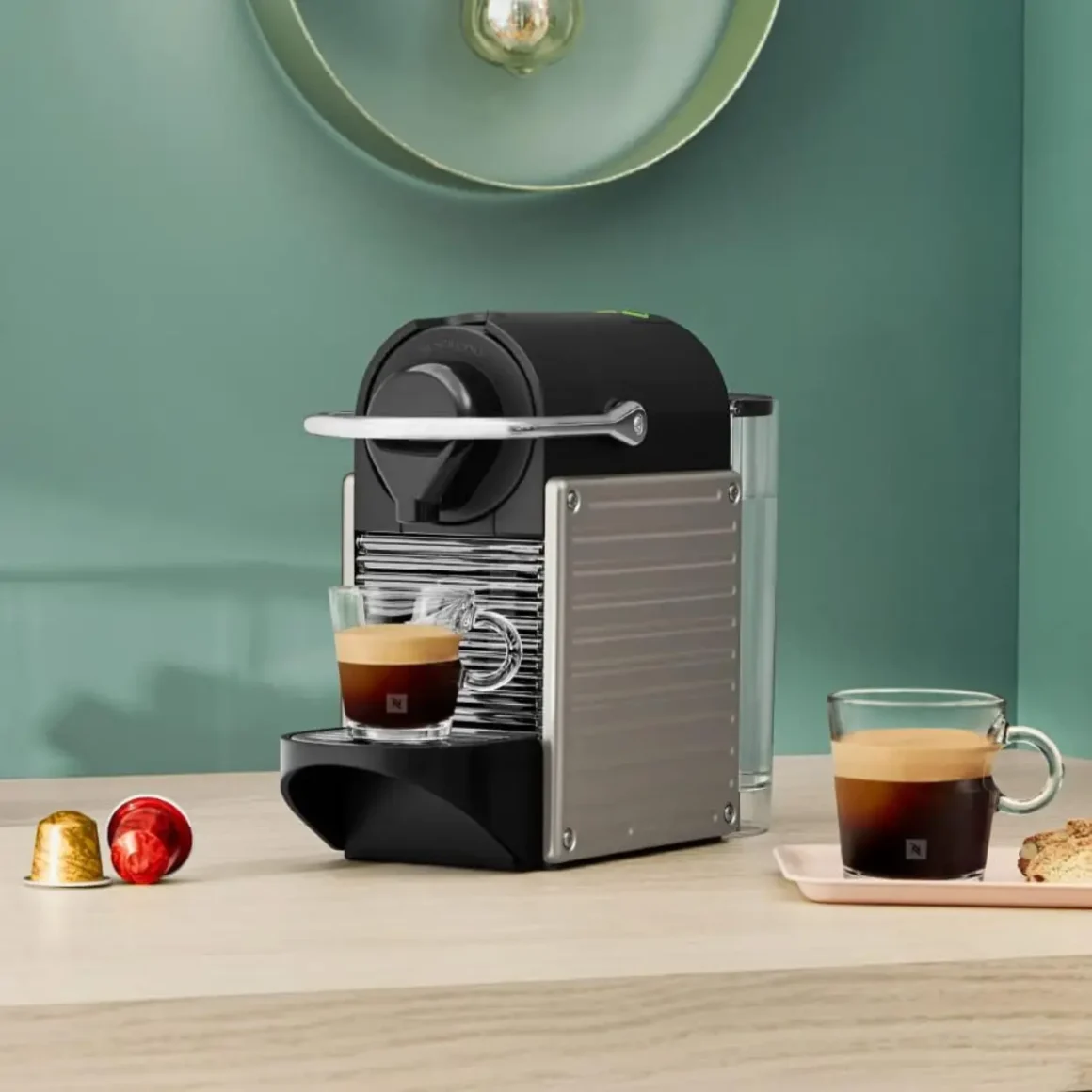 a nespresso pixie espresso machine on a table with two cups of coffee