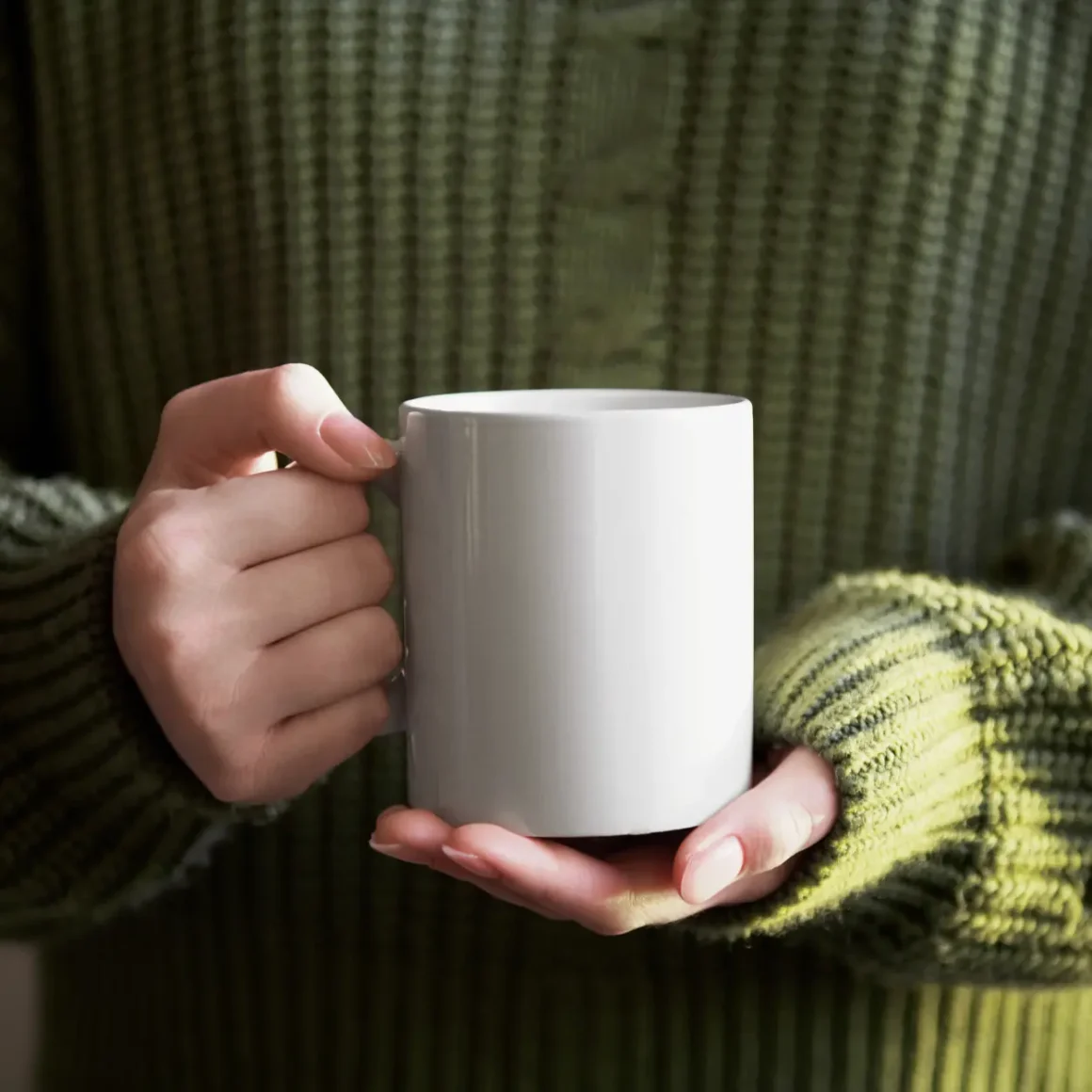 a person holding a white porcelain mug