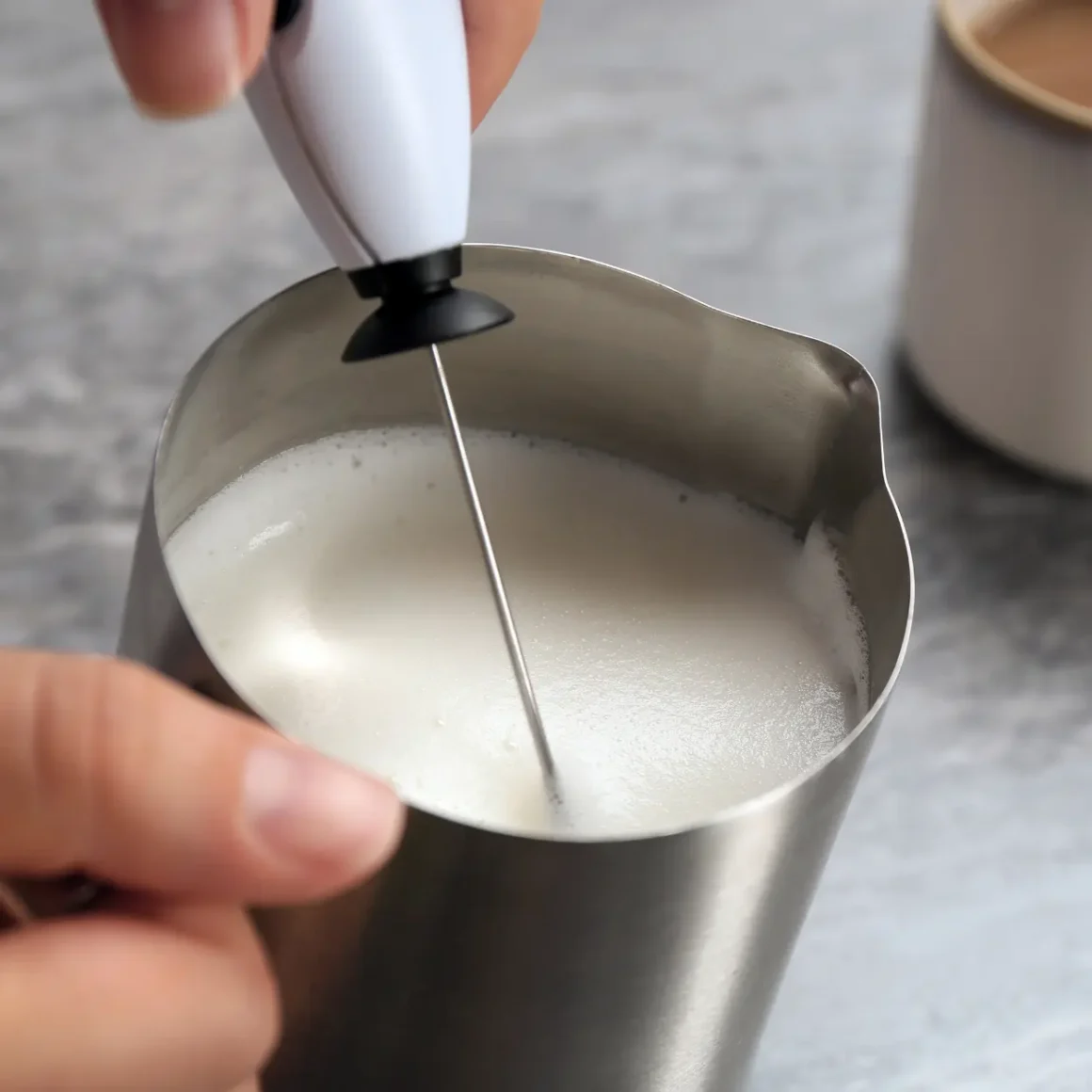 person using a milk frother to mix milk