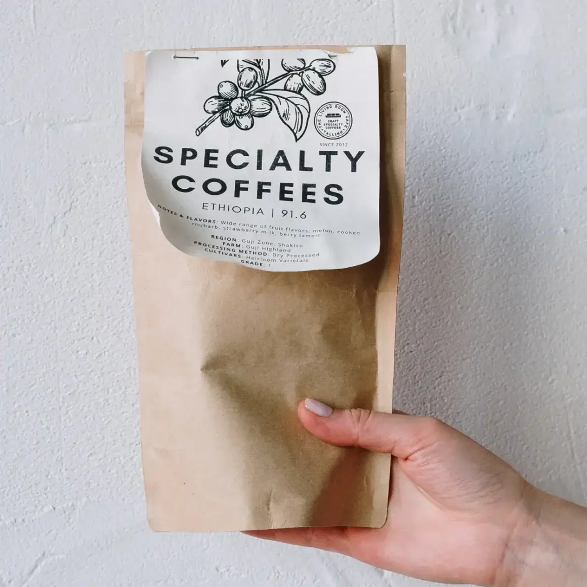 a hand holding a brown coffee beans bag