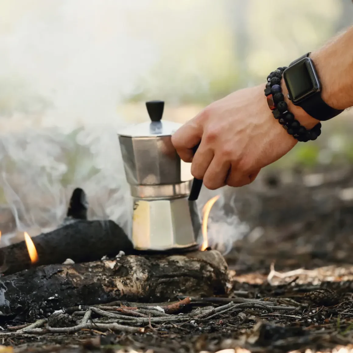a person using a moka pot over a fire