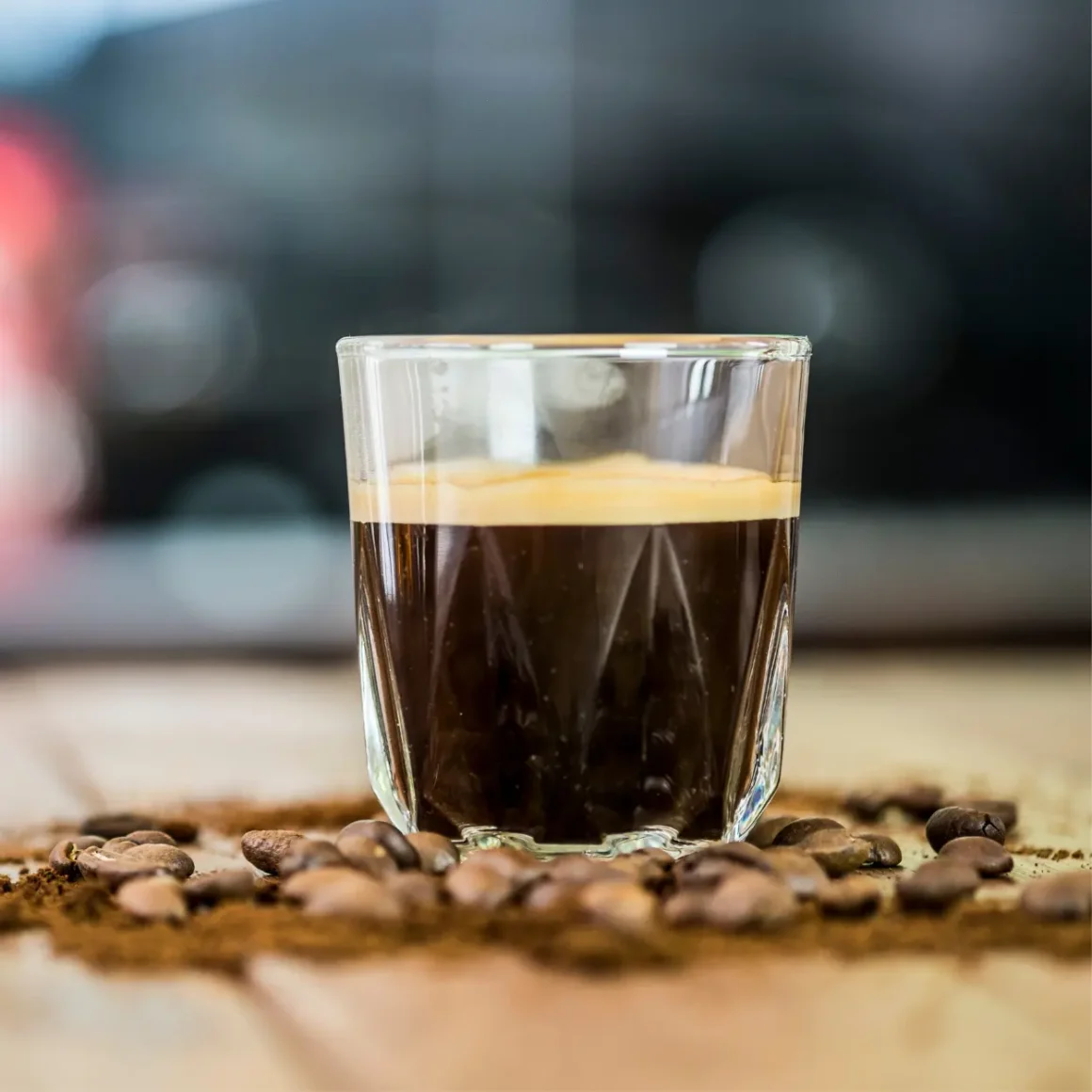 a glass of doppio espresso on top of coffee beans