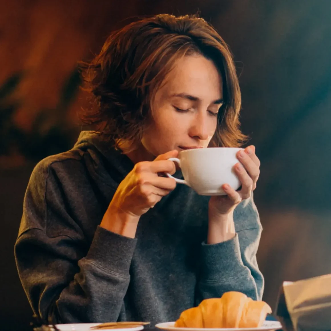 a woman drinking latte from a white cup
