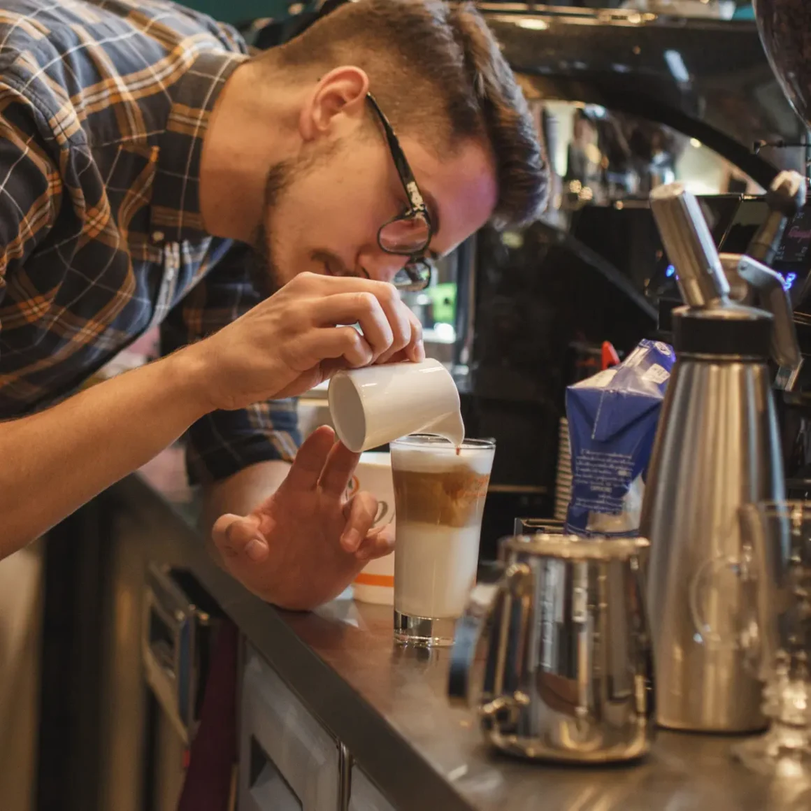 barista making a layered macchiato coffee