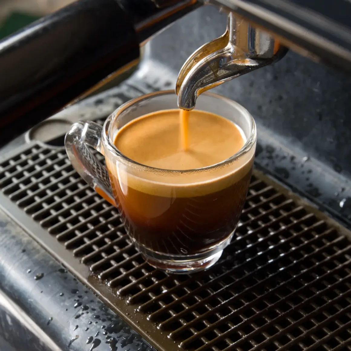 an espresso machine pouring a coffee into a glass cup