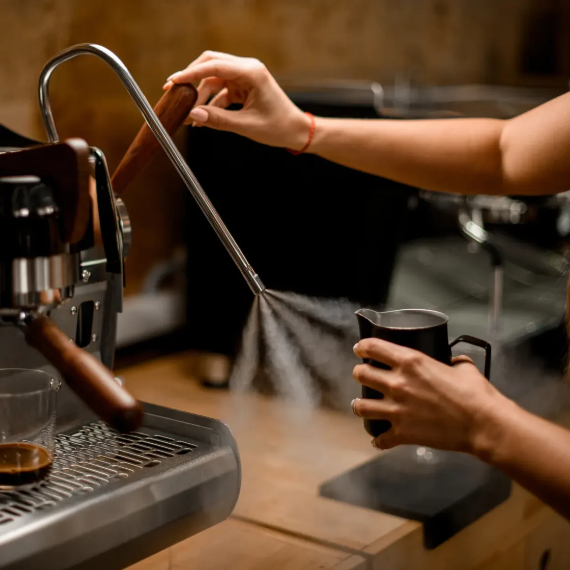 a person clearing the milk residue in a espresso machine frother