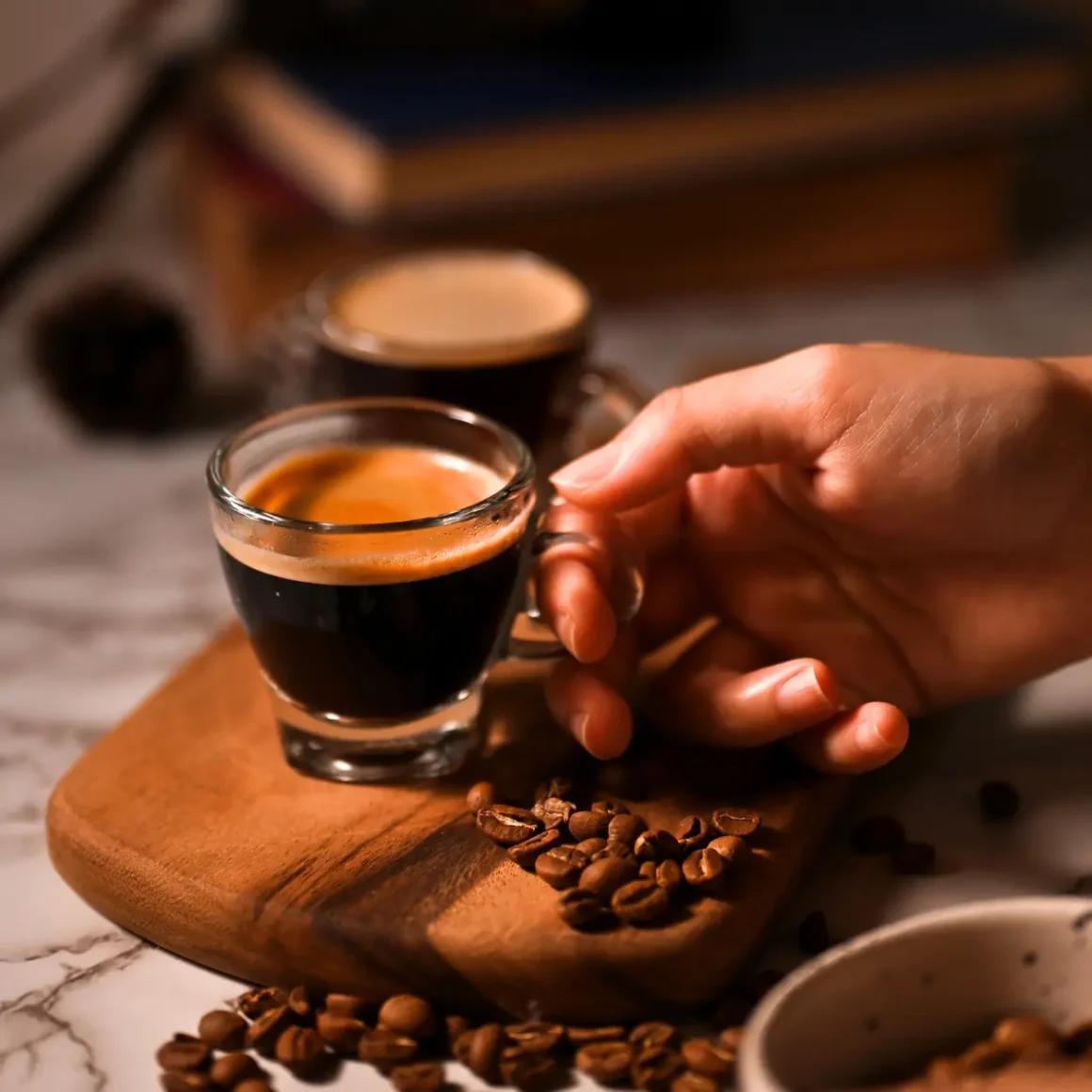 a hand holding a glass of doppio espresso
