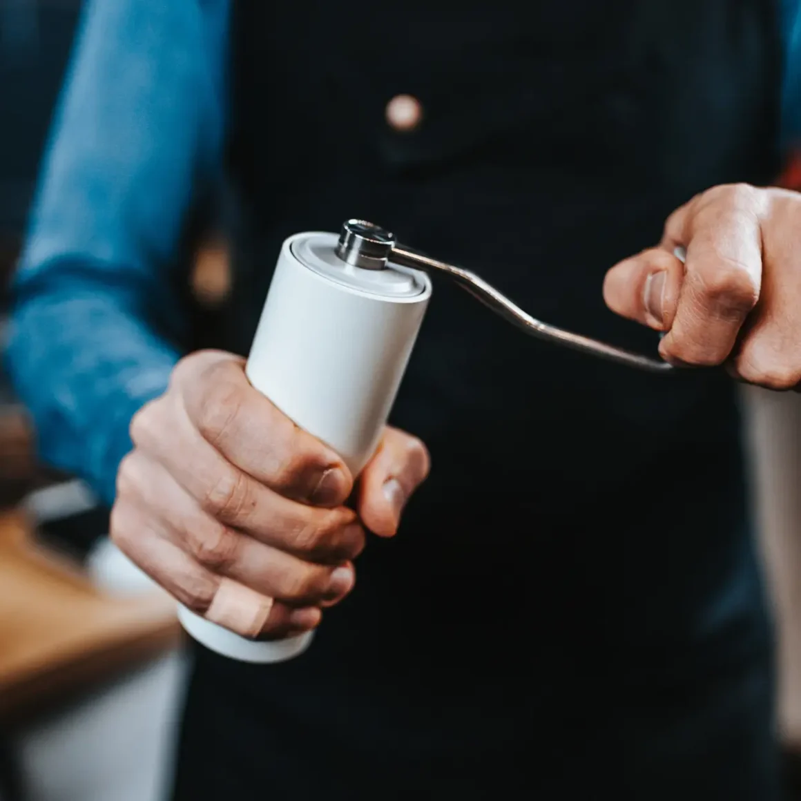 barista holding a white coffee grinder