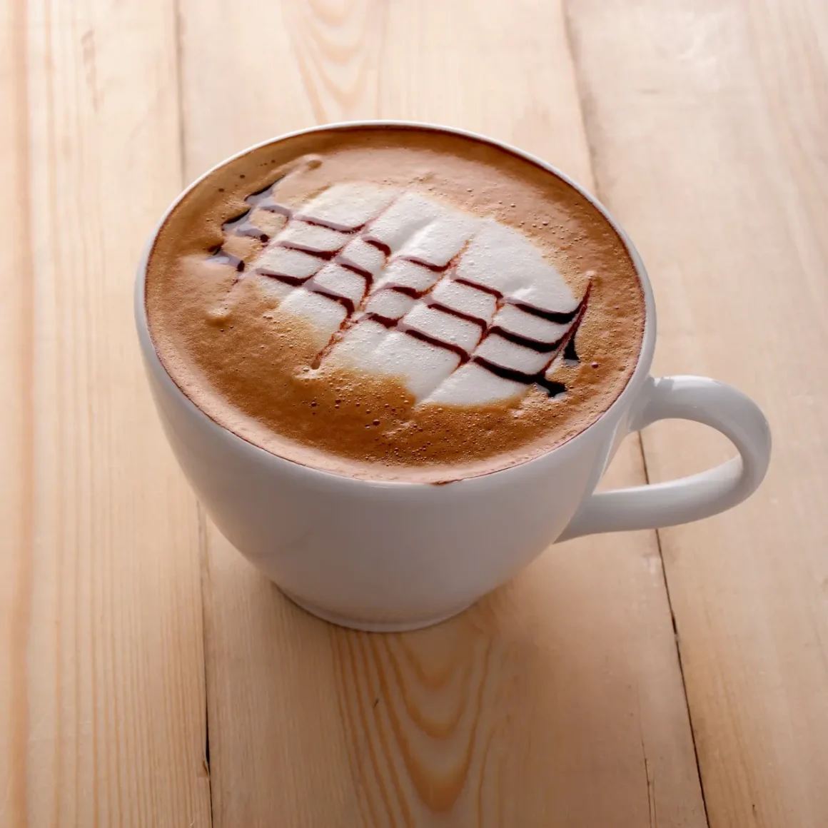 a cup of vanilla mocha with a design on the foam