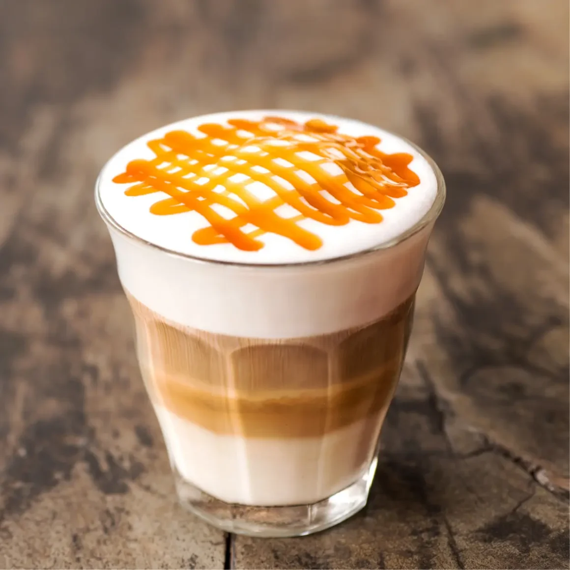 a glass of macchiato coffee with a caramel sauce on top