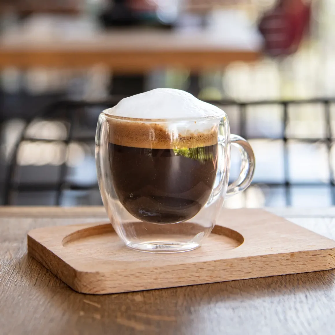 a glass cup of macchiato with foam on top