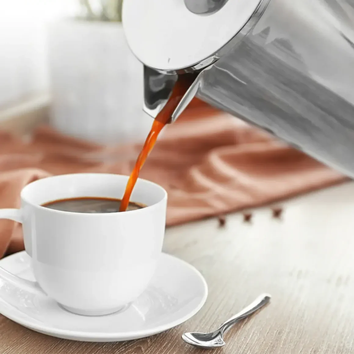 a coffee being poured into a cup from a mueller french press coffee maker