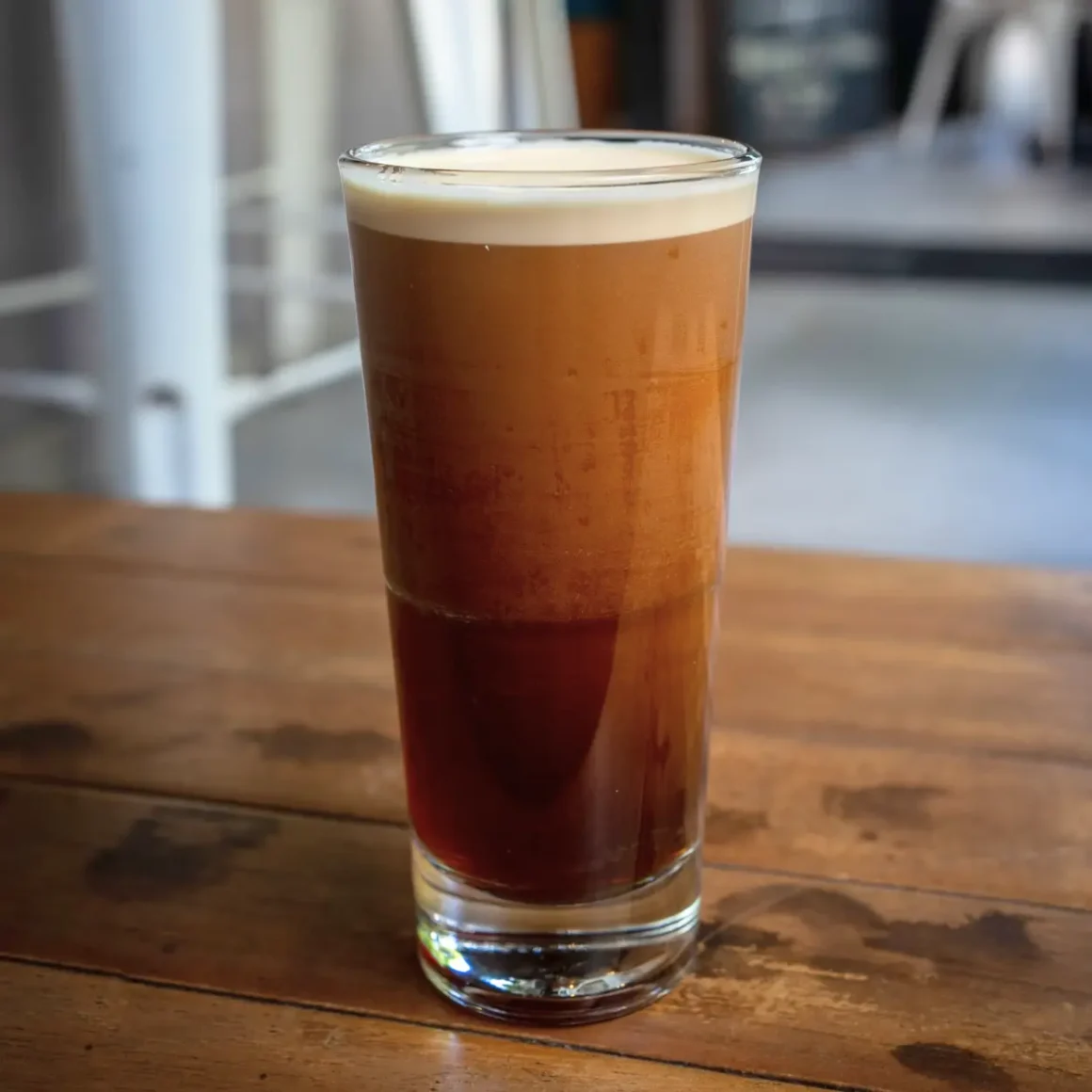 a glass of nitro cold brew coffee on a wooden table