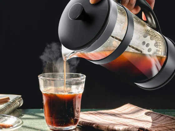 a person pouring a coffee into a glass from a utopia kitchen french press coffee maker