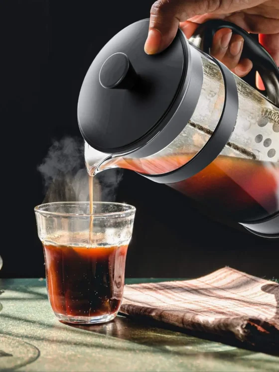 a person pouring a coffee into a glass from a utopia kitchen french press coffee maker