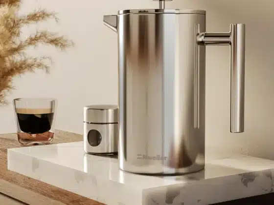 a silver mueller french press coffee maker and a glass of coffee on a marble counter