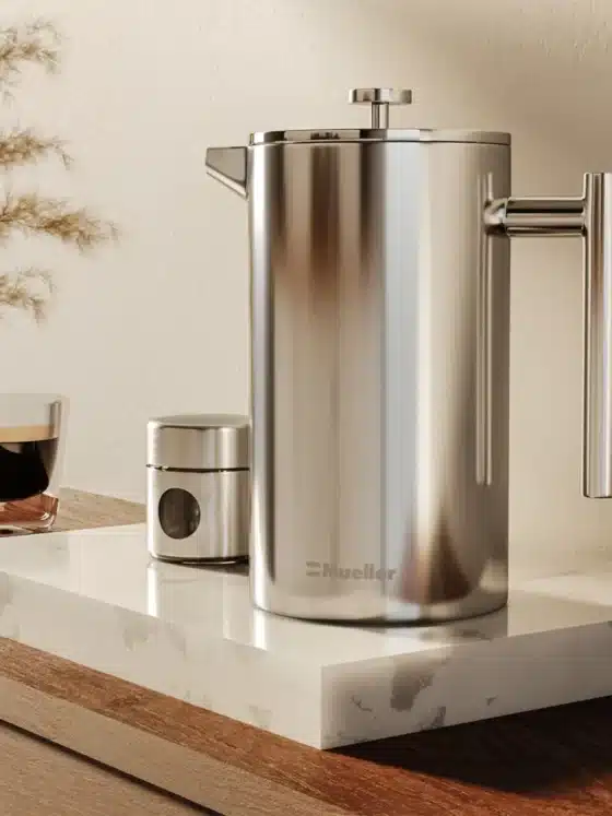 a silver mueller french press coffee maker and a glass of coffee on a marble counter