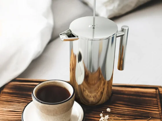 a utopia kitchen chrome double wall french press coffee maker and a cup of coffee on a tray