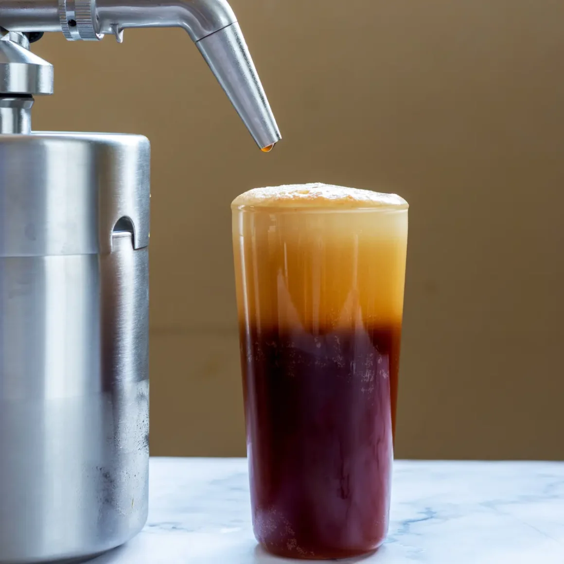a coffee machine and a glass of nitro cold brew coffee