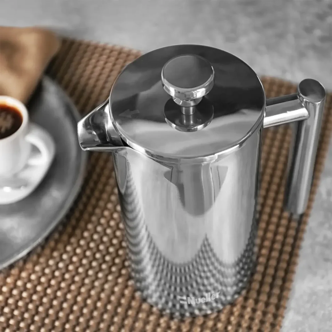 a silver mueller french press coffee maker on a brown mat