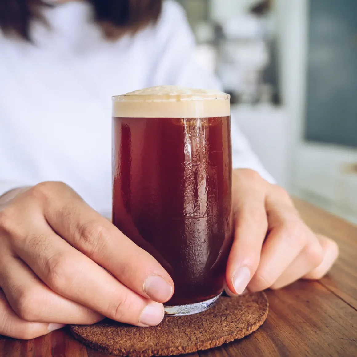 a person holding a glass of nitro cold brew coffee