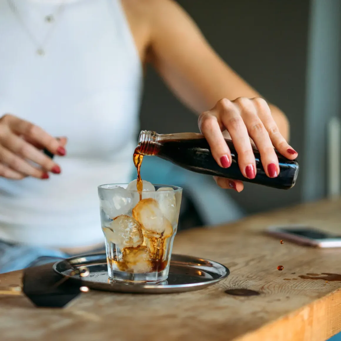 a person pouring nitro cold brew coffee into a glass