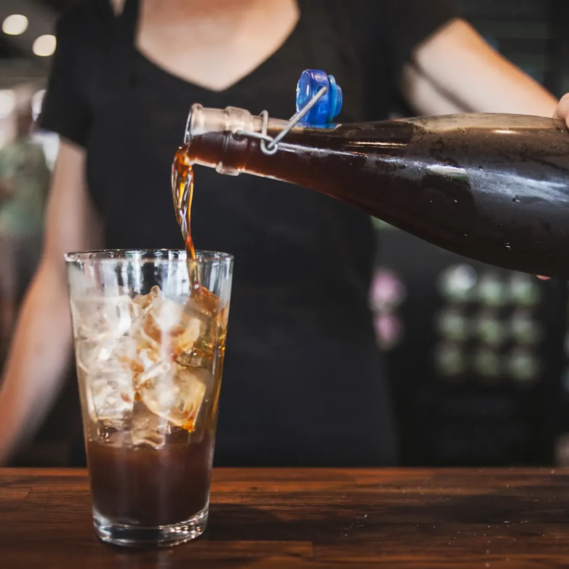 a person pouring a coffee into a glass